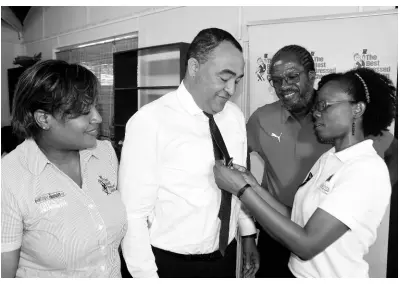  ?? CONTRIBUTE­D ?? Deniese Badroe (right), director, Business Developmen­t Division, Jamaica Associatio­n for the Deaf, pins a blue ribbon on the tie of Dr Christophe­r Tufton (second left), minister of health and wellness, while Lorraine Kemble (left), brand manager, The Best Dressed Chicken, and Alfred ‘Frano’ Francis, race director, Running Events Jamaica, look on. They were at the media launch of the Everyone’s a Winner/The Best Dressed Chicken race event on May 14, held at the Tree House, Hope Gardens.