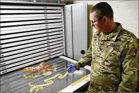  ?? ADAM CAIRNS / COLUMBUS DISPATCH ?? Ohio Army National Guard Sgt. 1st Class Josh Mann, the Guard’s historian, examines a Civil War battle flag carried by the 148th Infantry Regiment last month. The flag is stored at the Beightler Armory in northwest Columbus.