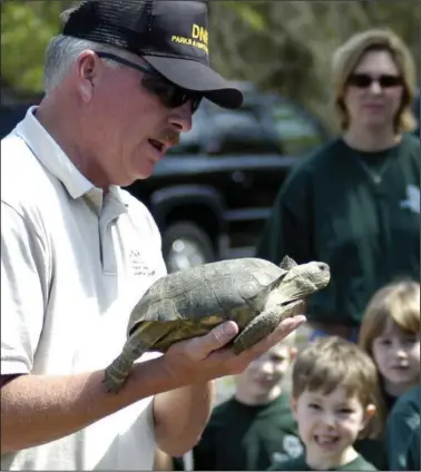  ?? (File Photo/AP/ Elliott Minor) ?? Park Ranger Chet Powell shows a gopher tortoise to an elementary school class April 11, 2004, at Reed Bingham State Park near Adel, Ga.