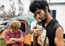  ?? TAMARA LUSH / AP ?? Ronald Lauricella cradles a kitten in his front yard in Bay County, Fla. The rural Bay County resident says some people who live on the outskirts of the cities aren’t getting needed services like electricit­y as fast as the more populated areas.