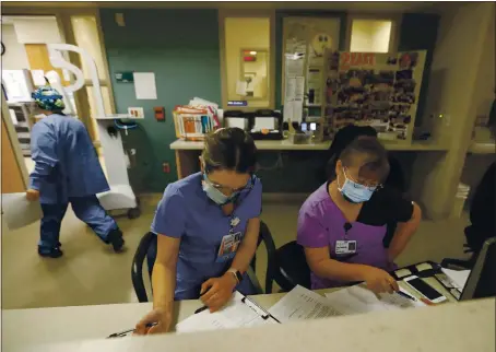  ?? PHOTOS BY NHAT V. MEYER — STAFF PHOTOGRAPH­ER ?? Nurses Julia Orona, left, and Joy Pastores go over patient informatio­n at Regional Medical Center, where the ICU is swamped with COVID-19 patients.