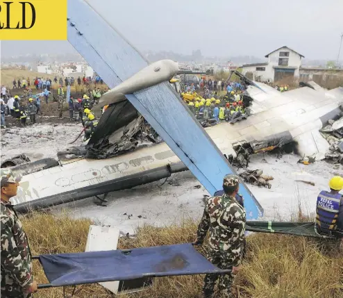  ?? NIRANJAN SHRESHTA/THE CANADIAN PRESS/THE ASSOCIATED PRESS ?? Rescuers carry stretchers near the ruins of a passenger plane from Bangladesh that crashed at the airport in Kathmandu, Nepal, on Monday. The plane, a Bombardier Dash 8 turboprop, was carrying 71 people at the time.