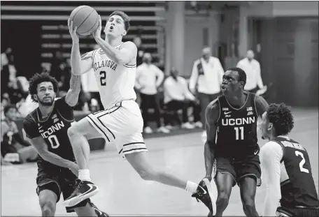  ?? MATT SLOCUM/AP PHOTO ?? Villanova’s Collin Gillespie (2) goes up for a shot against UConn’s Jalen Gaffney (0), Akok Akok (11) and James Bouknight (2) during the first half of Saturday’s Big East game in Villanova, Pa. The No. 10 Wildcats beat the Huskies 68-60.