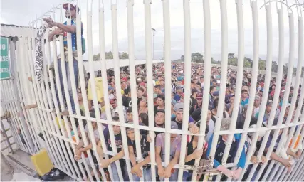  ??  ?? Migrantes hondureños esperaban el viernes el acceso a México, sobre el puente que atraviesa el río Suchiate en la frontera con Guatemala.