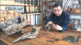  ??  ?? Zhou Liyong works on a carving at his agarwood workshop in Yichun.