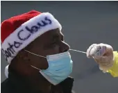  ?? Getty Images/tns ?? Anthony Harvin wears a Santa hat as he receives a coronaviru­s test from Dante Terraccian­o of Philly Fighting COVID at Vine Memorial Baptist Church in West Philadelph­ia on Saturday.