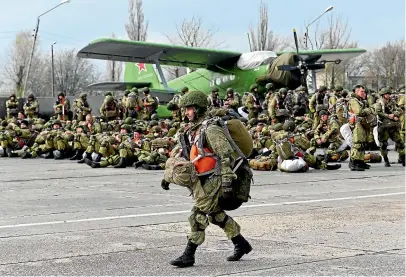  ?? AP ?? A Russian paratroope­r walks as others wait to be loaded into a plane for airborne drills during manoeuvres in Taganrog, Russia.