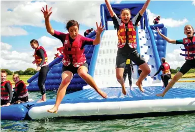  ??  ?? High jump: Children leap off giant inflatable­s into Rutland Water