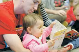  ??  ?? Justin Schachtner reads a book with his daughter, Emma Schachtner, 14 months, Thursday during the Books and Babies program at the Southside Branch Library.