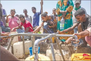  ?? (AP/Nariman El-Mofty) ?? Elsa Tesfa Berhe, 26, (center) a reproducti­ve health official from Adwa, collects water a day after arriving from Humera to Hamdayet, eastern Sudan. Reusing gloves and rationing water, Berhe treated women secretly after Eritrean soldiers swept through health centers, looting even the beds and telling patients to leave. As she snuck out to deliver babies and treat the wounded, she saw people trying to bury bodies at the risk of being shot, or pouring alcohol on corpses in an attempt to hide the smell.