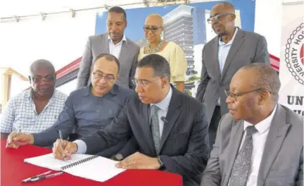  ?? (Photo: Garfield Robinson) ?? Prime Minister Andrew Holness (seated, third left) signing a contract for the rerouting of the University Hospital of the West Indies (UHWI) ring road at the ground-breaking ceremony on Tuesday on the hospital grounds. He is joined by Minister of Health and Wellness Dr Christophe­r Tufton (seated, second left); Fitzgerald Mitchell, acting CEO of UHWI (right) and contractor for the ring road project Benton Woodbine looks on. Standing (from left) are Dr Carl Bruce, medical chief of staff at the UHWI; Fayval Williams, MP for St Andrew Eastern; and Patrick Hylton, chairman of the UHWI.