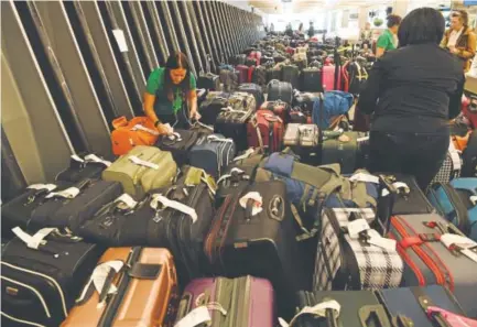  ?? Photos by Andy Cross, The Denver Post ?? A Frontier Airlines employee, left, checks tags on rows and rows of unclaimed baggage at Denver Internatio­nal Airport on Dec. 20. The baggage remained unclaimed after a big snowstorm four days earlier.