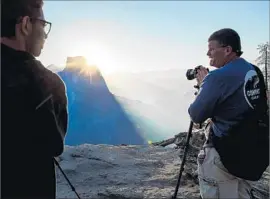  ?? Marcus Yam Los Angeles Times ?? VISITORS WATCH the sun rise behind Half Dome in smoke-shrouded Yosemite National Park. Tourists have been disappoint­ed by the decrease in visibility.