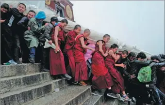  ?? PHURBU TASHI / XINHUA ?? Monks at Drepung Monastery carry a rolled thangka to celebrate the annual weeklong shoton festival in Lhasa, Tibet autonomous region, on Saturday. Unrolled, the religious image is 40 meters long and 37 meters wide.