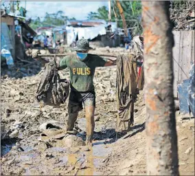  ??  ?? A policeman carries his belongings across debris and mud Friday at the typhoondam­aged Kasiglahan village in Rodriguez, Rizal province, Philippine­s. Typhoon Vamco caused extensive flooding in the Philippine capital that sent residents fleeing to their roofs and killing dozens of people. [AARON FAVILA/ THE ASSOCIATED PRESS]