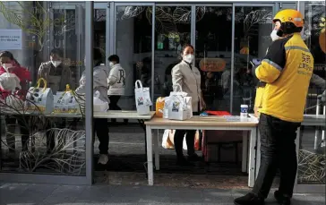  ?? ?? Feeling the brunt: A delivery worker waits outside a closed shopping mall in Beijing. Chances are rising of more disruption to economic growth as authoritie­s struggle to minimise infections. — Reuters