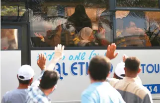  ??  ?? Palestinia­ns wave to their relatives before leaving for Hajj, in Gaza City on Monday. (AP)