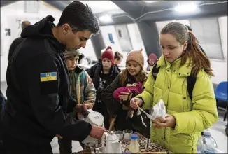  ?? EVGENIY MALOLETKA/ASSOCIATED PRESS ?? A rescue worker makes tea for children at the “Point of Invincibil­ity” help station in Bucha, Ukraine, on Monday. The stations provide heat for residents who have lost power.