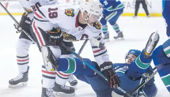  ?? DARRYL DYCK/THE CANADIAN PRESS ?? Canucks captain Henrik Sedin falls to the ice in front of Chicago Blackhawks counterpar­t Jonathan Toews on Thursday night at Rogers Arena.