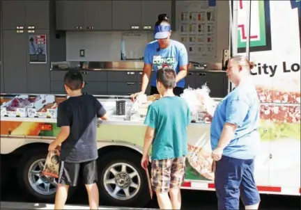  ?? TAWANA ROBERTS — THE NEWS-HERALD ?? Painesvill­e Schools Nutrition Services Staff Lorina Meeks and Tessie Hacker assists children at The Lunch Box, the mobile summer food program that provides free nutritious lunches to children and teens 18 years or younger, on July 31.