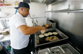  ??  ?? Enrique Salas, owner of Taqueria Gracias Madre, prepares an order of tacos on Monday.