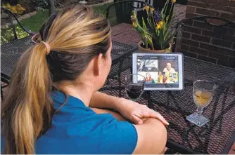  ?? OLIVIER DOULIERY AFP VIA GETTY IMAGES ?? A woman enjoys a virtual happy hour using Houseparty, an app from Epic Games that allows up to eight people to chat together in virtual rooms. The app had 50 million new sign-ups in the last month.