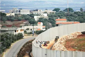  ?? — Reuters photo ?? An Israeli crane is seen by a wall built near the border, as seen from Lebanon, near the village of Kfarkila, in south Lebanon.