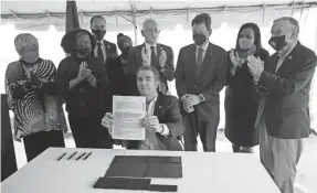  ?? STEVE HELBER/AP ?? Virginia Gov. Ralph Northam, seated, displays a bill abolishing the death penalty after signing it as he is surrounded by legislator­s and activists at Greensvill­e Correction­al Center in Jarratt, Va., on March 24.