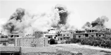  ??  ?? Smoke rises above buildings during an airstrike by Syrian regime forces on the town of Busra al-Harir, east of the southern Syrian province of Daraa. — AFP photo