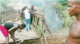  ?? PHOTOS: Linus Effiong ?? Youths of the community removing what is left of the collapsed bridge