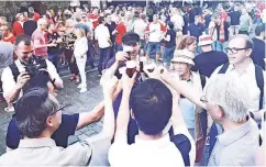  ??  ?? Sänger des Männerchor­s des Japanische­n Clubs stoßen auf der Ratinger Straße mit Passanten an.
