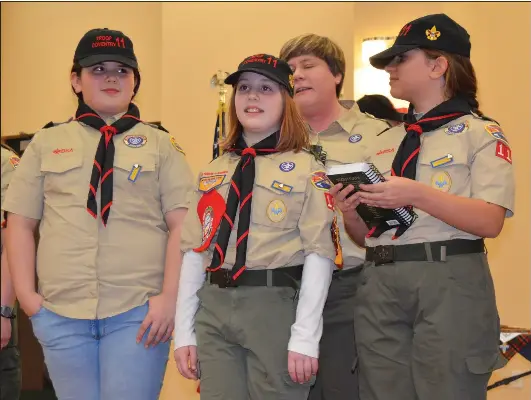  ?? Photos by Kendra Gravelle ?? Samantha Robinson, scoutmaste­r of the newly-formed Troop 11 G Coventry, dubs in her daughter Emma Robinson during a crossover ceremony at Saints John and Paul Church Thursday evening. Also pictured are Kristyana Tabulina, left, and Emily Mayer.