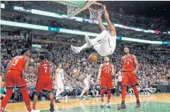  ?? AP ?? The Celtics’ Al Horford hangs from the rim after dunking against the Raptors.