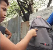  ?? GABRIEL BONJOC ?? A 12-year-old girl shows her bandaged right leg where she was hurt by a bullet from the police operation in Talisay City Tuesday night. At right, the girl's cousin shows the hole in his backpack that another bullet pierced. The two were walking...