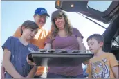  ?? Samie Gebers/The Signal ?? The Stacey family looks down at their baked cookies while they cool in a Valencia parking lot on Saturday.