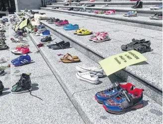  ?? JASON PAYNE • POSTMEDIA NEWS ?? Two hundred-and-fifteen pairs of kids' shoes line the steps of the Vancouver Art Gallery on May 28 in response to the revelation that 215 children's remains were discovered this week at the site of the former Kamloops residentia­l school. The shoes were placed on the steps by First nations advocates from the Downtown Eastside.