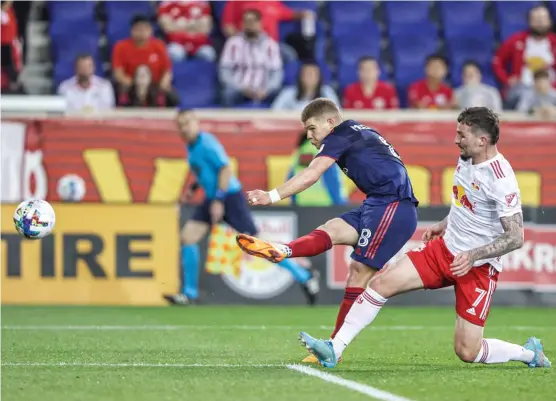  ?? VINCENT CARCHIETTA/USA TODAY SPORTS ?? Midfielder Chris Mueller scores his first goal for the Fire as Red Bulls defender Tom Edwards tries to impede him in the first half.