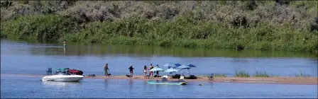  ??  ?? PEOPLE SET UP UMBRELLAS, CHAIRS AND OTHER EQUIPMENT early Thursday morning apparently in anticipati­on of a long, relaxing day on a sandbar in the Colorado River.