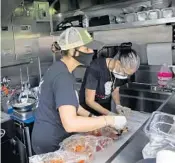  ??  ?? Lauren Grosso, left, and her mother, Pam Grosso, cook July 13 at Papamigos mobile kitchen, a food truck used as a test kitchen on the site where their permanent restaurant is to be built in Pompano Beach.