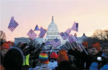  ??  ?? President Barack Obama supporters wave American flags Monday on the National Mall in Washington before the start of Obama’s ceremonial swearing-in during the 57th presidenti­al Inaugurati­on.
BUSINESS