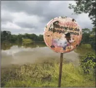  ??  ?? A hippo warning stands on the shore of a lagoon near Doral, Colombia.