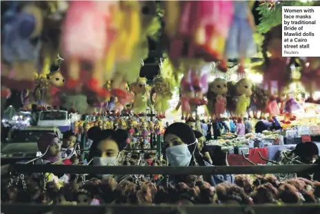  ?? Reuters ?? Women with face masks by traditiona­l Bride of Mawlid dolls at a Cairo street stall