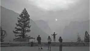  ?? NOAH BERGER/AP ?? Hannah Whyatt poses for a friend’s photo as smoke fills Yosemite Valley in 2018 in Yosemite National Park, Calif. Wildfires burning across much of the nation this summer have upended plans for countless outdoor adventures.