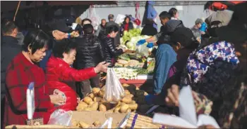  ??  ?? A woman (2nd from left) buys potatoes at a market in Beijing. China’s factory inflation eased in October owing to slackening demand and a trade war with the United States, while consumer price inflation held steady, official data showed yesterday.