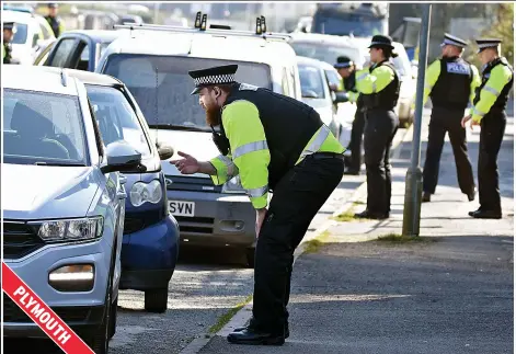  ??  ?? Keep your distance...officers stop and quiz a huge queue of motorists about their destinatio­n yesterday