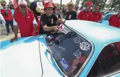  ?? ?? TENGKU Ahmad Badli Shah menampal pelekat Agro Bank sebelum melepaskan konvoi 350 Volkswagen klasik ke Masjid Kampung Laut ketika ditemui di Pantai Geting, Tumpat.