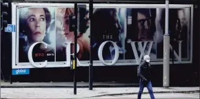  ?? Matt Dunham / Associated Press ?? A man wearing a face mask walks past a billboard, on Nov. 20, advertisin­g ‘ The Crown’ television series about Britain’s Queen Elizabeth II and the royal family, during England’s second coronaviru­s lockdown, in London. Britain’s Culture Secretary Oliver Dowden in a newspaper interview published Sunday, said he thinks “The Crown” should come with a disclaimer as it’s a work of fiction with historical liberties taken in the Netflix drama about the British royal family.