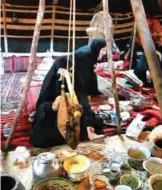  ??  ?? A woman uses the traditiona­l way of making Arabic ghee and butter by manually shaking the milk inside a special container made out of goat skin.