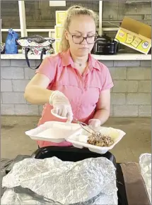  ?? Tamara Johnson • Times-Herald ?? Carlie Bothum, St. Francis County Extension Agent for 4-H and livestock, places barbecue onto a plate Thursday afternoon during a fundraiser at the Wiley T. Jones Fairground­s. Several animals were also at the fairground­s for children to pet while learning more about the county’s 4-H programs.