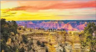  ?? Getty Images / iStockphot­o ?? VISITORS enjoy a sunset above the canyon from the Mather Point lookout on the South Rim.